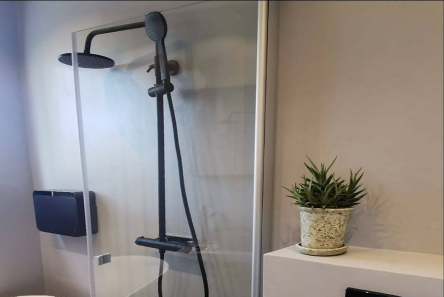 En duschvägg i ett badrum med väggar i microcement